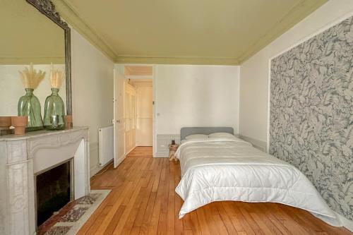 une chambre blanche avec un lit et une cheminée dans l'établissement Flexliving - room - Bachaumont, à Paris