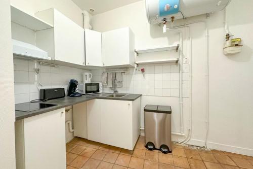 - une cuisine avec des armoires blanches et une poubelle dans l'établissement Flexliving - room - Échiquier, à Paris