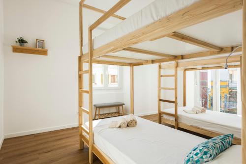 two bunk beds in a room with white walls and wooden floors at Madalena Hostel e Suites in Faro