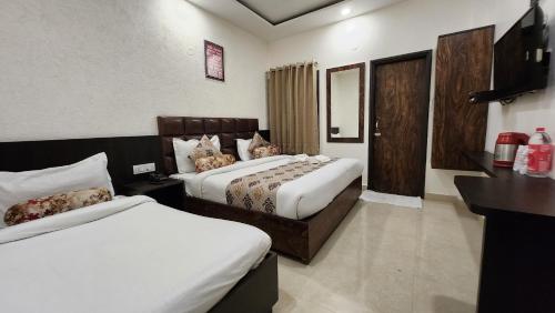 a hotel room with two beds and a television at Hotel Krishnas in Amritsar