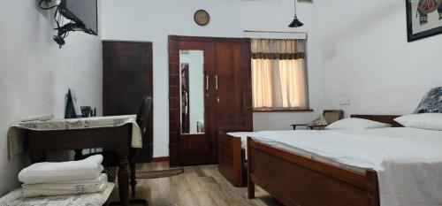 a bedroom with a bed and a desk and a sink at CHARAKAMA Guest Bungalow - GAMPAHA in Gampaha