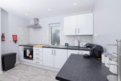 a kitchen with white cabinets and a black counter top at MODERN 2 BeD APARTMENT in Enniskillen