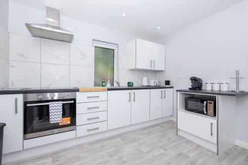a white kitchen with white cabinets and appliances at MODERN 2 BeD APARTMENT in Enniskillen