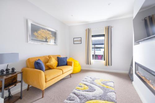 a living room with a yellow couch and a tv at MODERN 2 BeD APARTMENT in Enniskillen