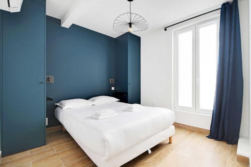 une chambre avec un grand lit blanc avec des murs bleus dans l'établissement Refreshing 2BD-6P apartment - 18th ard, à Paris