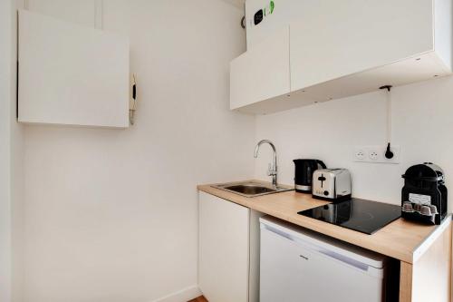 une petite cuisine avec des armoires blanches et un évier dans l'établissement Cozy studio - 2P - Grenelle-Eiffel Tower, à Paris
