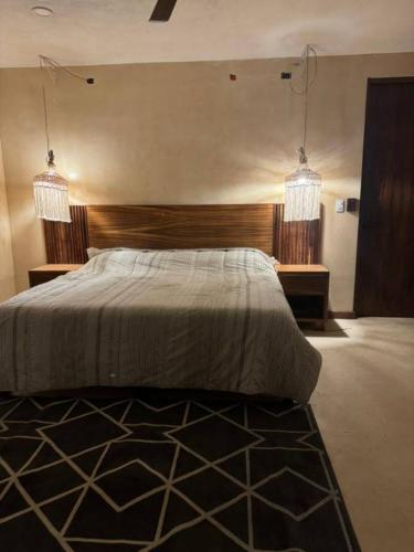 a bedroom with a large bed with two chandeliers at Villa Natural en Chemuyil in Balcheil