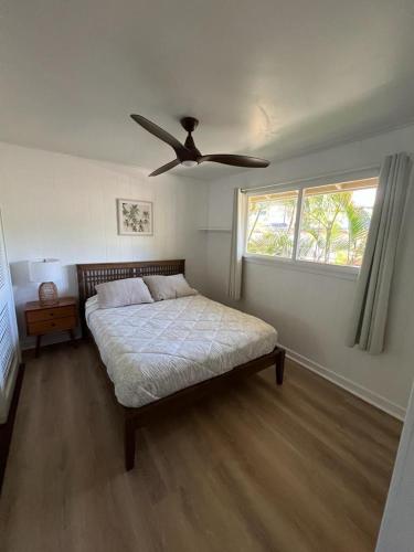 a bedroom with a bed and a ceiling fan at Waimea Bay Garden Bunglaow in Haleiwa