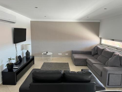 a living room with a couch and a tv at Modern 2 Bed Apartment 5km Carvoeiro in Lagoa