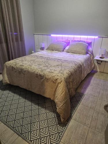 une chambre avec un grand lit avec un éclairage violet dans l'établissement Gite du Chêne Pardaillan, à Pardaillan