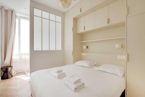 une chambre avec un lit blanc avec des serviettes dessus dans l'établissement Spacieux Appartement cosy -2BR 8P-Pl de la Nation, à Paris