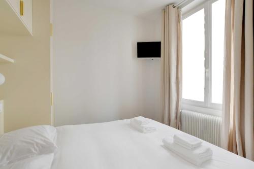 un lit blanc avec deux serviettes dessus dans l'établissement Spacieux Appartement cosy -2BR 8P-Pl de la Nation, à Paris