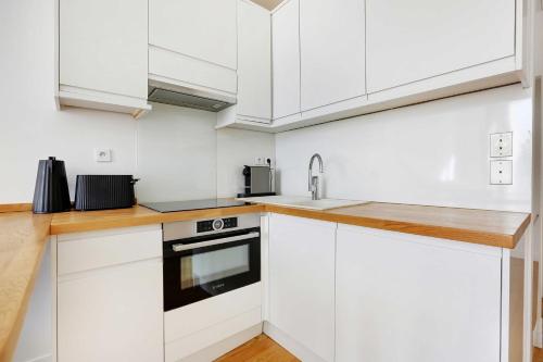 une cuisine avec des armoires blanches et un évier dans l'établissement Cosy & chic studio - 2P - Levallois, à Levallois-Perret