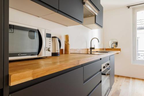 Il comprend une cuisine équipée d'un four micro-ondes et d'un comptoir en bois. dans l'établissement Chic appartement - 1BR-4P - Château de Vincennes, à Vincennes