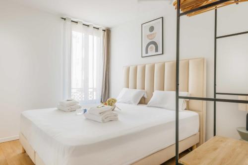 une chambre avec un grand lit blanc avec deux serviettes dans l'établissement Chic appartement - 1BR-4P - Château de Vincennes, à Vincennes