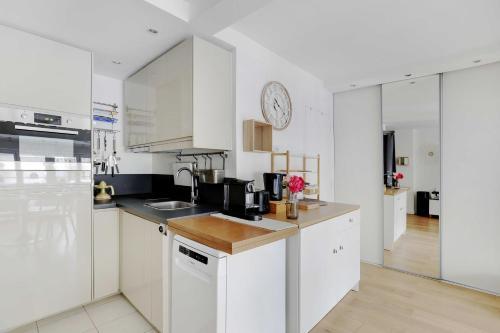une cuisine avec des placards blancs et une horloge murale dans l'établissement Cozy studio - 2P - Place de la Bourse, à Paris