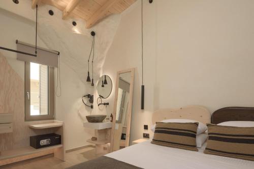 a bedroom with a bed and a sink and a mirror at Manili Boutique Suites & Villas in Archanes