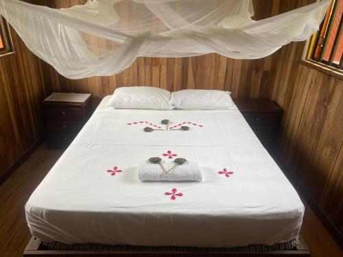 a bed with two towels and flowers on it at Cabaña El Bien Germina Ya in El Valle