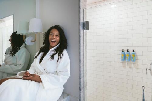 a woman laughing in front of a mirror in a bathroom at Gardiner House in Newport
