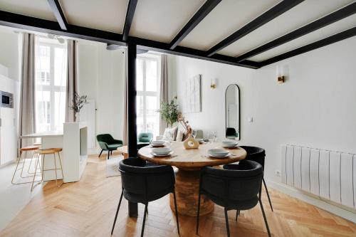 une salle à manger avec une table en bois et des chaises noires dans l'établissement Charming Apartment - 1BR-5P - Sentier, à Paris