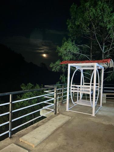 a white fence with a gate and a white bench at The Shalam Resort श्रीकृष्ण शरणं मम in Lansdowne