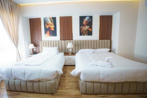 two beds in a hotel room with white sheets at Pyramids Sunshine View in Cairo