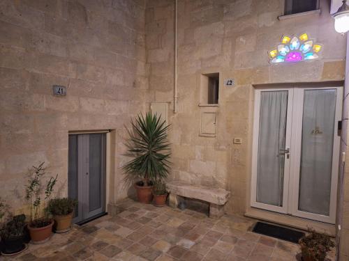 a stone wall with a bench and plants in a courtyard at La Teresina Holiday Homes in Matera