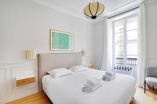 une chambre avec un lit blanc avec deux serviettes dessus dans l'établissement Appartement Moderne Champs-Elysées - Saint Honoré, à Paris