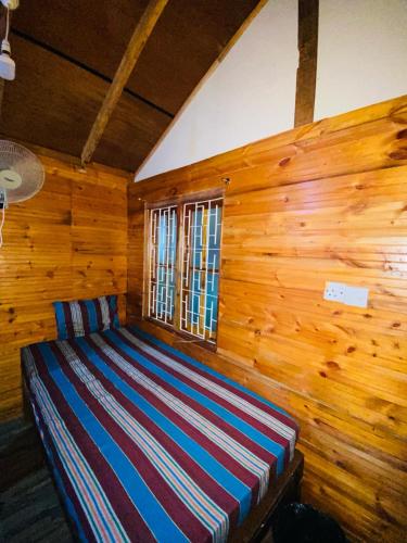 a bed in a room with a wooden wall at Alffa Guest Inn in Trincomalee