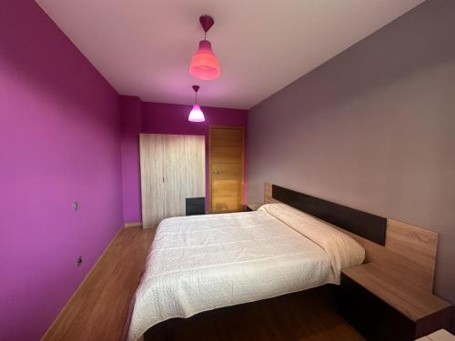 a bedroom with a bed with purple walls and two lights at Disfruta del pirineo oscense in Sabiñánigo