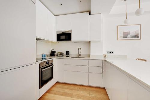 une cuisine blanche avec des armoires et des appareils blancs dans l'établissement Passy - Eiffel Tower - Amazing 2BR with garden, à Paris