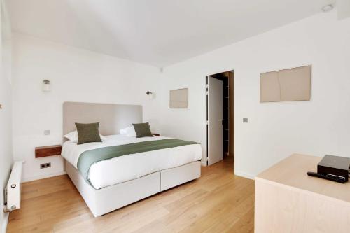 une chambre blanche avec un lit et un bureau dans l'établissement Passy - Eiffel Tower - Amazing 2BR with garden, à Paris
