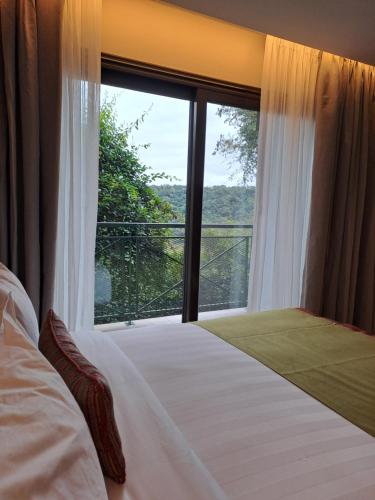 a bedroom with a bed and a large window at Iguazu Jungle Lodge in Puerto Iguazú