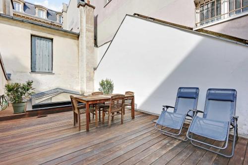 une terrasse en bois avec une table et deux chaises dans l'établissement Cozy appartment avec Terrace - 2BR-4P - Centre de Paris, à Paris