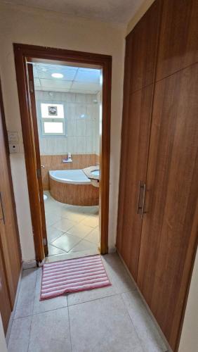 Un baño con bañera y una puerta que da a otro baño con alfombra. en Splendid Private Rooms, en Sharjah