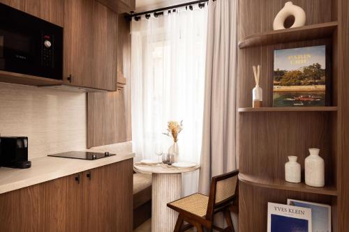 Cette chambre comprend une cuisine avec une table et une fenêtre. dans l'établissement Magnificent Studio with A-C - 2P - Champs-Élysées, à Paris