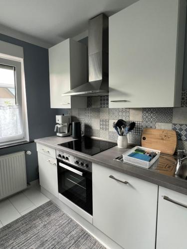 a kitchen with white cabinets and a stove top oven at Ferienwohnung Kasia in Medebach