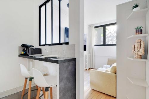 une cuisine avec un comptoir et des tabourets dans une pièce dans l'établissement Cozy studio - 2P - Batignolles-Parc-Monceau, à Paris
