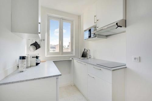 une cuisine blanche avec des armoires blanches et une fenêtre dans l'établissement Cosy apartment - 1BR-2P - Near Champs-de-Mars, à Paris