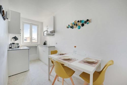 une cuisine blanche avec une table blanche et des chaises jaunes dans l'établissement Cosy apartment - 1BR-2P - Near Champs-de-Mars, à Paris