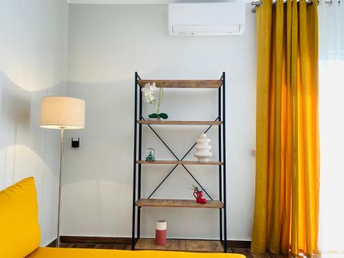 a shelf in a living room with a yellow curtain at Adora City Center in Divjakë