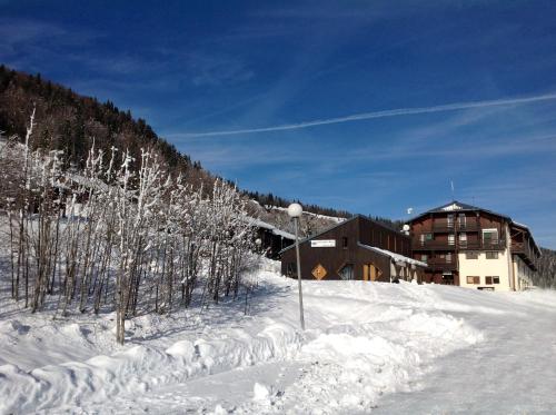 a building on a snow covered slope with trees at Hôtel Club Le Risoux in Bois-dʼAmont
