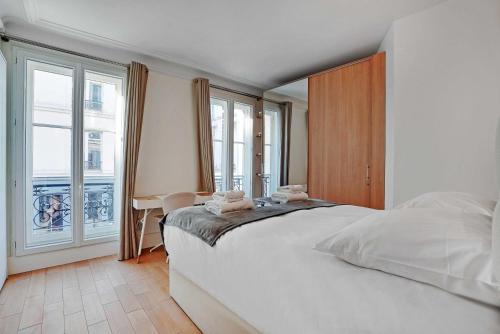 une chambre avec un grand lit blanc et un bureau dans l'établissement Cosy apartment - 2BR-6P - Saint-Germain-des-Prés, à Paris