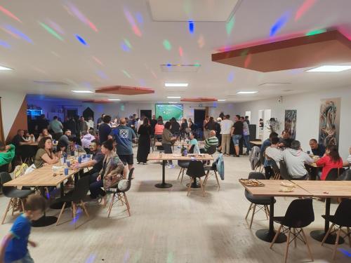 un groupe de personnes assises à des tables dans une pièce dans l'établissement Camping aux 4 vues, à Saint-Papoul