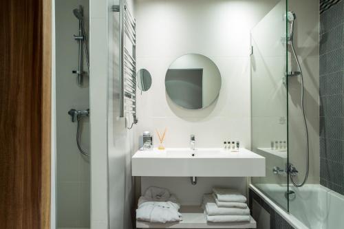 Baño blanco con lavabo y espejo en Hotel Atrium by Happyculture en Suresnes