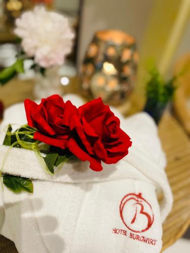 a red rose sitting on top of towels on a table at Hotel Burgwirt in Deggendorf