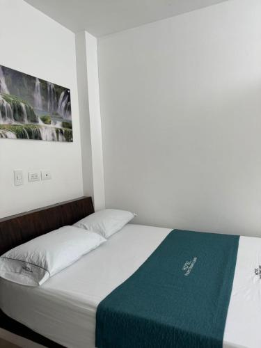 a bedroom with a bed with a green blanket at Hotel Puerto Triunfo in Doradal