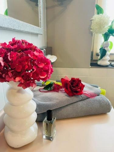 a white vase with red flowers on a table at Hotel Burgwirt in Deggendorf