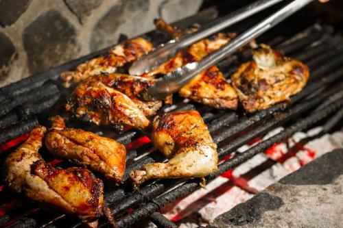 a bunch of chicken on a grill with tongs at La Iguana Perdida in Santa Cruz La Laguna