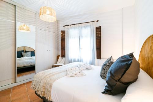 a bedroom with a white bed and a mirror at Wekey Homes, Casa del Albaicyn in Granada